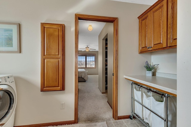 laundry room featuring baseboards, cabinet space, washer / dryer, and light carpet