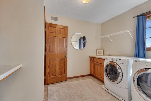 washroom with visible vents, cabinet space, baseboards, and washing machine and dryer