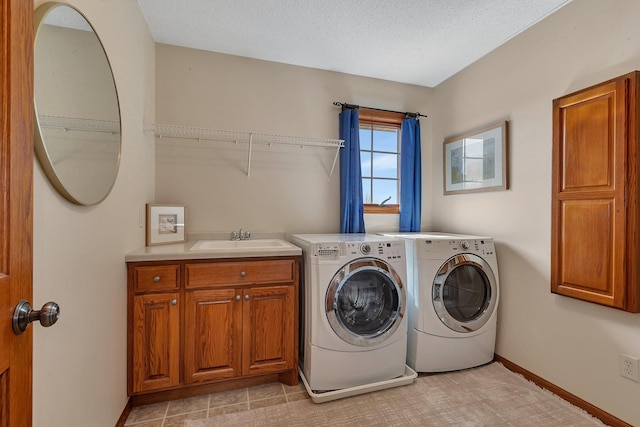 laundry room with a sink, washer and dryer, a textured ceiling, cabinet space, and baseboards