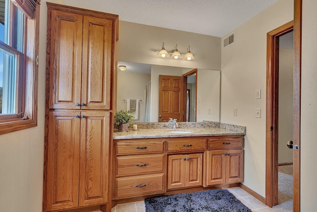 full bathroom with visible vents, baseboards, vanity, tile patterned floors, and a textured ceiling