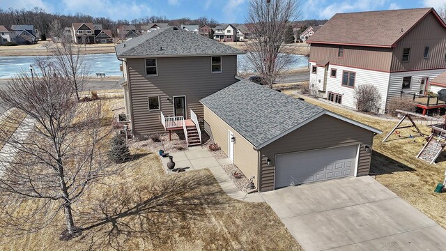 exterior space with a residential view, concrete driveway, a shingled roof, and a garage