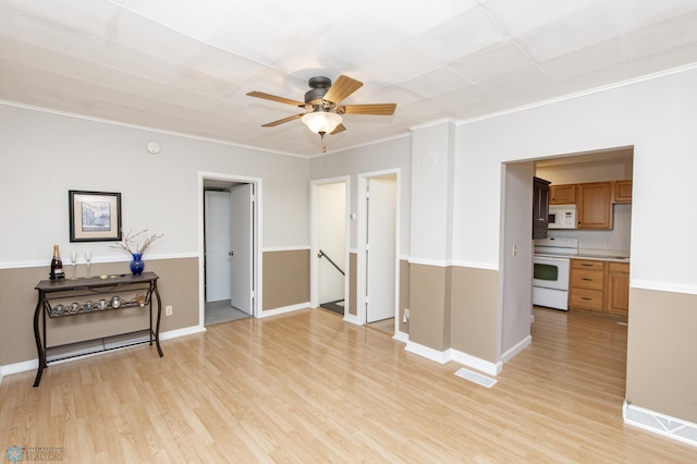 spare room featuring baseboards, light wood finished floors, visible vents, and crown molding