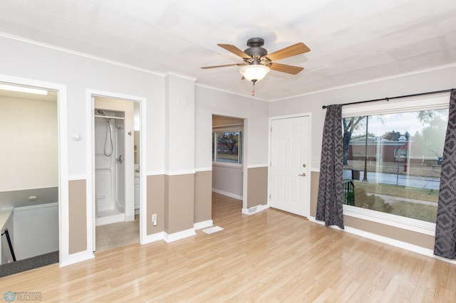 spare room with crown molding, light wood-style flooring, baseboards, and ceiling fan