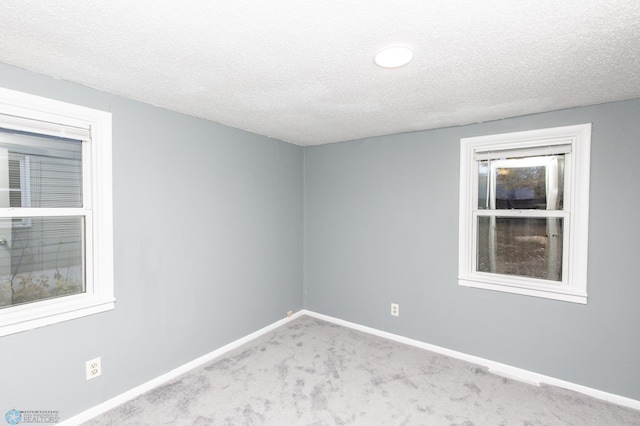 carpeted spare room featuring baseboards and a textured ceiling