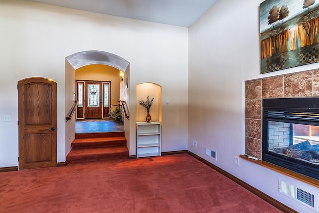 entryway featuring baseboards, a tiled fireplace, visible vents, and carpet flooring