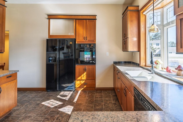 kitchen featuring black appliances, stone finish floor, a sink, and brown cabinets