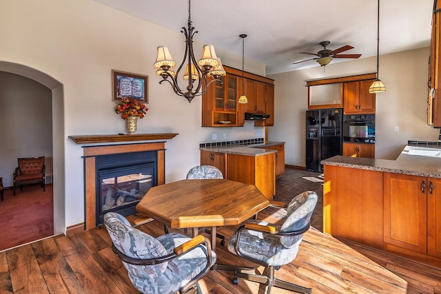 kitchen featuring brown cabinetry, black fridge with ice dispenser, glass insert cabinets, a peninsula, and a multi sided fireplace