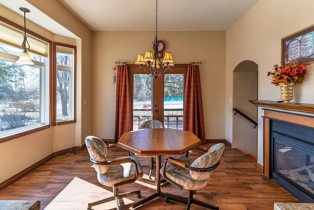 dining room with dark wood-style floors, arched walkways, a notable chandelier, and baseboards