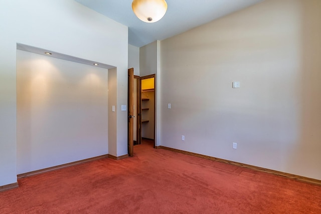 empty room featuring light carpet, vaulted ceiling, and baseboards