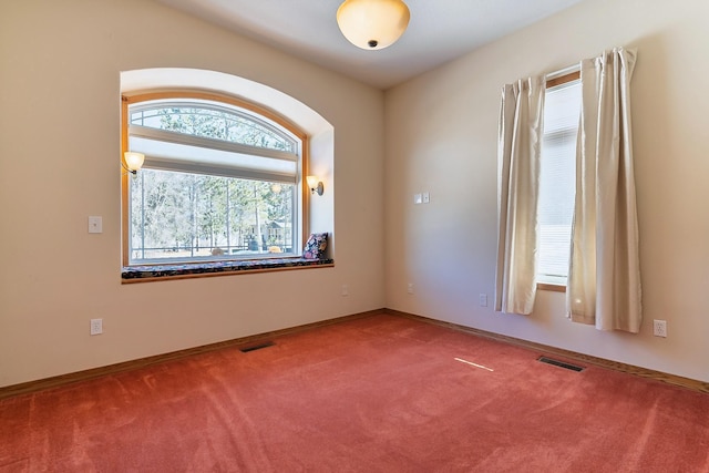 empty room with carpet flooring, visible vents, and baseboards