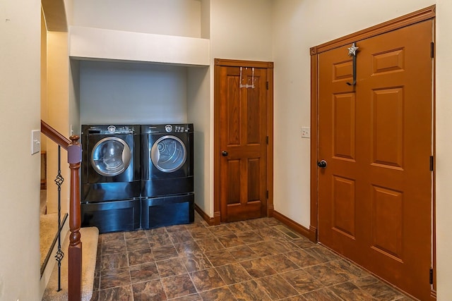 washroom featuring laundry area, stone finish flooring, baseboards, and washer and clothes dryer