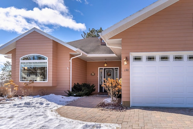 view of front of home featuring a shingled roof, decorative driveway, and an attached garage