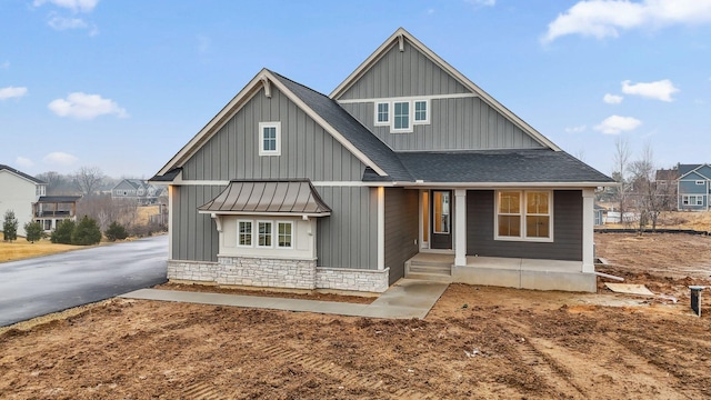 view of front of house with a shingled roof, board and batten siding, a standing seam roof, metal roof, and stone siding