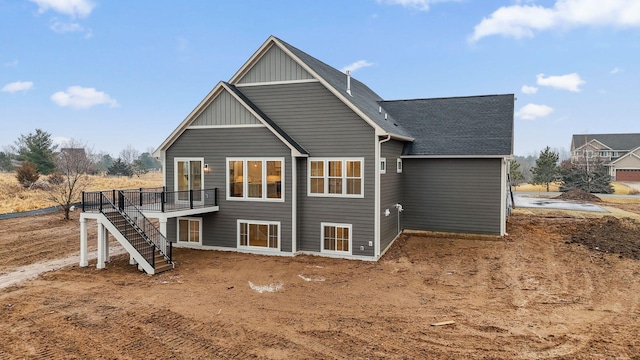 back of property with board and batten siding, a shingled roof, stairway, and a deck