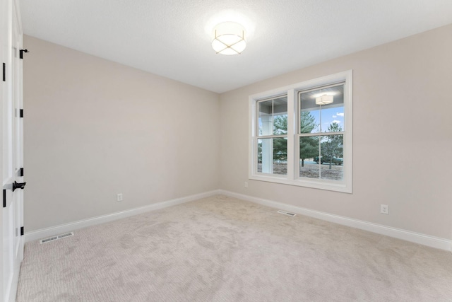 carpeted spare room featuring visible vents and baseboards