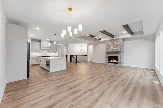 kitchen featuring open floor plan, light countertops, beam ceiling, and light wood-style floors