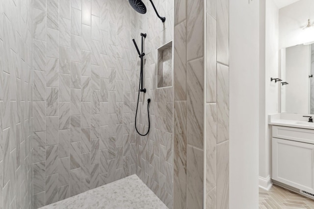 bathroom featuring tiled shower and vanity