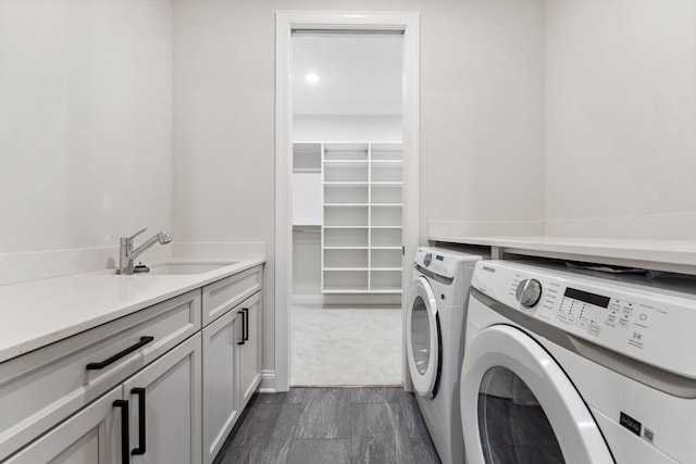 washroom featuring cabinet space, dark wood-type flooring, a sink, and washing machine and clothes dryer