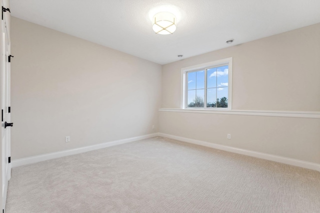 spare room featuring baseboards and light colored carpet