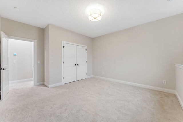 unfurnished bedroom featuring a closet, light colored carpet, and baseboards