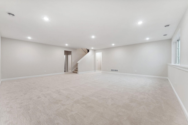 finished below grade area featuring stairway, light colored carpet, visible vents, and recessed lighting