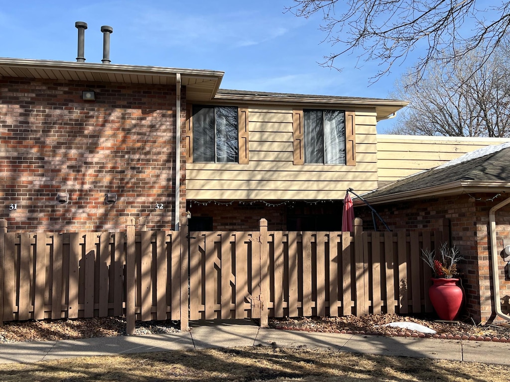 view of side of home featuring brick siding and a fenced front yard