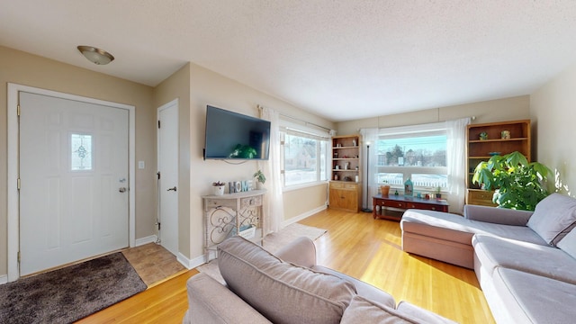 living area featuring a textured ceiling, baseboards, and wood finished floors