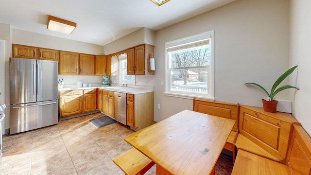 kitchen with stainless steel appliances, brown cabinetry, a sink, and light countertops