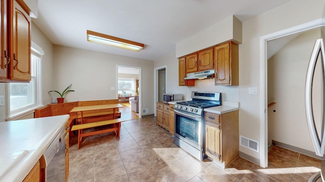 kitchen with visible vents, stainless steel appliances, light countertops, under cabinet range hood, and light tile patterned flooring