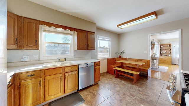 kitchen with brown cabinets, stainless steel appliances, a sink, and light countertops