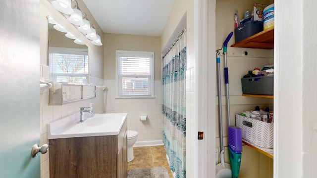 full bath with tile walls, curtained shower, toilet, vanity, and tile patterned flooring