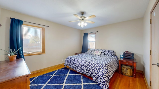 bedroom featuring a ceiling fan, baseboards, and wood finished floors