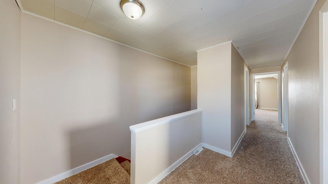 hall with carpet floors, ornamental molding, an upstairs landing, and baseboards