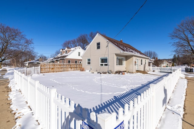 snow covered house with a fenced backyard