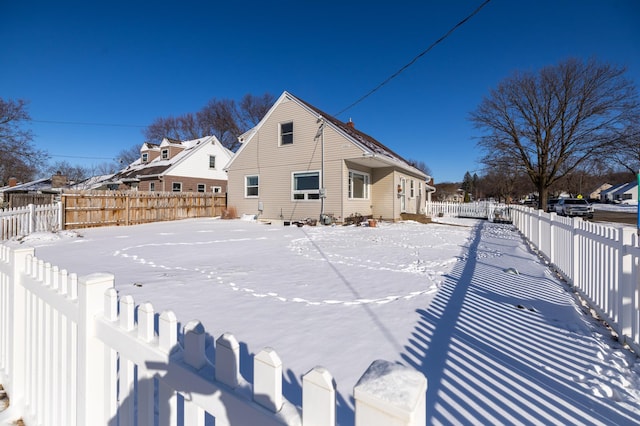 snow covered rear of property with a fenced backyard