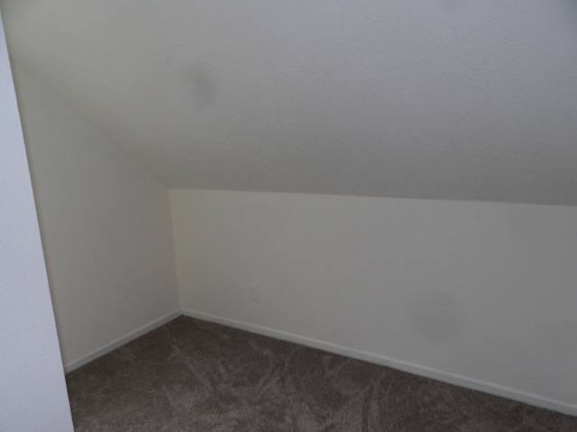 bonus room with lofted ceiling, baseboards, and dark colored carpet