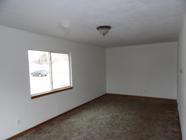 unfurnished room with a textured ceiling, carpet flooring, and baseboards