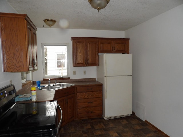 kitchen with electric range, visible vents, brown cabinets, freestanding refrigerator, and a sink