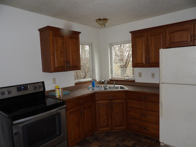 kitchen with freestanding refrigerator, a sink, electric range, and dark countertops