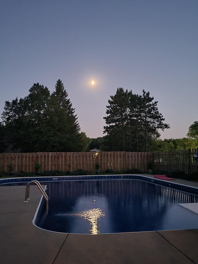 pool at dusk featuring a fenced in pool and fence