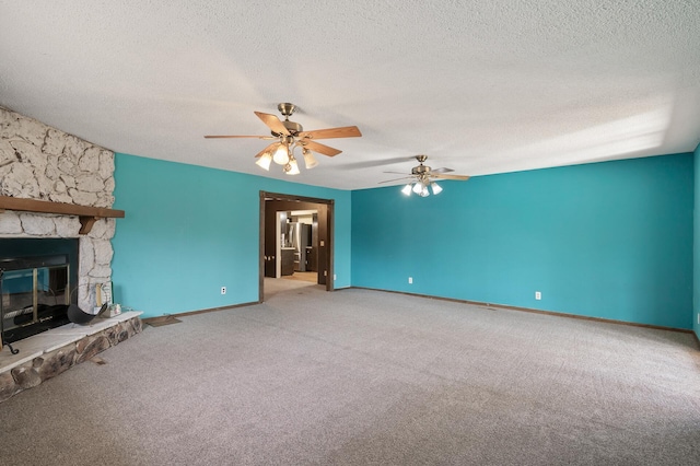 unfurnished living room featuring baseboards, carpet, a stone fireplace, a textured ceiling, and a ceiling fan