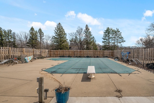 view of pool with a patio, a diving board, a fenced backyard, and a fenced in pool