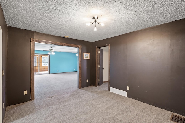 spare room with carpet flooring, baseboards, visible vents, and a textured ceiling