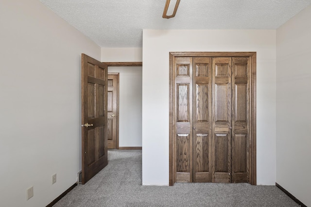 unfurnished bedroom featuring baseboards, carpet floors, a textured ceiling, and ceiling fan