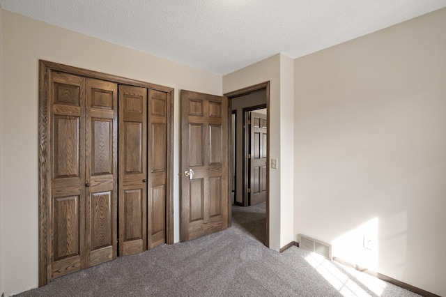 unfurnished bedroom featuring visible vents, carpet, and a textured ceiling