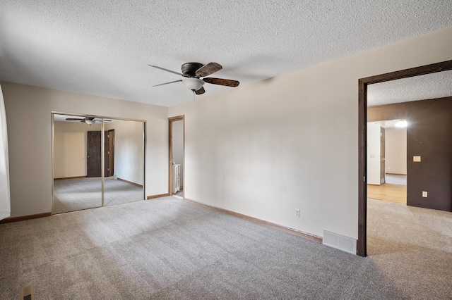 unfurnished bedroom with visible vents, carpet, a closet, and a textured ceiling