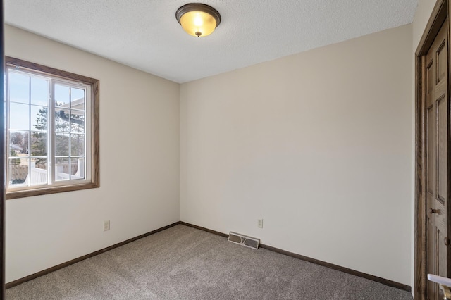 spare room with baseboards, visible vents, carpet floors, and a textured ceiling