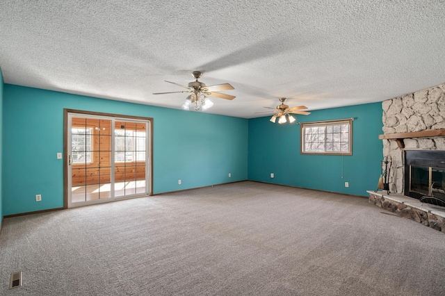 unfurnished living room with a ceiling fan, visible vents, a fireplace, a textured ceiling, and carpet flooring