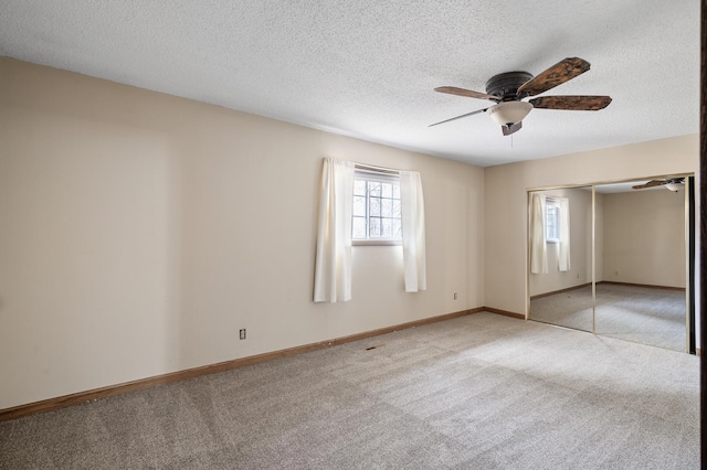 unfurnished bedroom featuring baseboards, ceiling fan, a closet, a textured ceiling, and light carpet