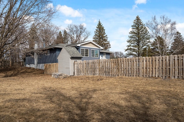 view of home's exterior with roof with shingles and fence